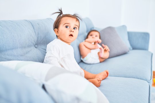 Beautiful infant happy girls playing together at home kindergarten sitting on the sofa