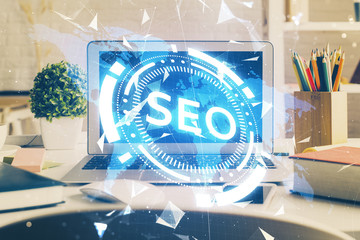 Double exposure of table with computer and seo drawing hologram. Search optimization concept.