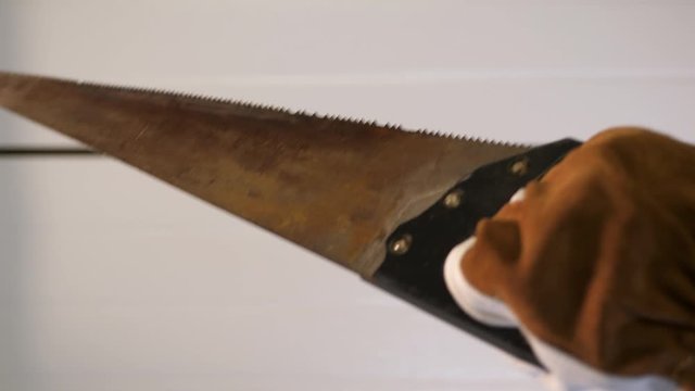 Construction worker holding old rusty hand Saw. Home worker with brown white gloves. POV.