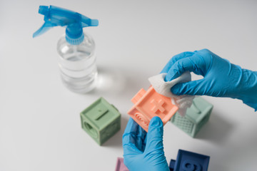 Hands in nitrile gloves are cleaning and disinfecting toys
