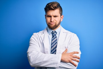 Young blond therapist man with beard and blue eyes wearing coat and tie over background skeptic and nervous, disapproving expression on face with crossed arms. Negative person.