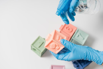 Hands in nitrile gloves are cleaning and disinfecting toys