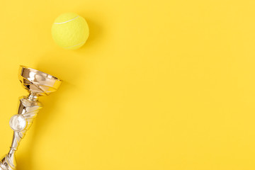 Champion trophy cup and tennis ball isolated on geometric yellow background. Minimalistic...