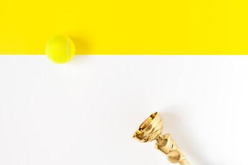 Champion trophy cup and tennis ball isolated on geometric white and yellow background. Minimalistic composition with copy space. Sports achivments.Top view, flatlay
