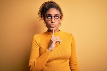 Young beautiful african american girl wearing sweater and glasses over yellow background Thinking...