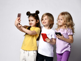 Young children take selfie with mobile phone broadcast online hold cellphones in hands on white