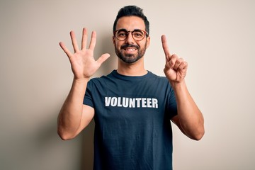 Handsome man with beard wearing t-shirt with volunteer message over white background showing and...