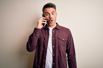 Young handsome man having conversation talking on the smartphone over white background scared in shock with a surprise face, afraid and excited with fear expression