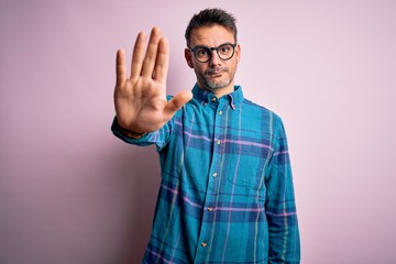 Young handsome man wearing casual shirt and glasses standing over isolated pink background doing...