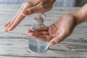 Young woman using hand sanitizer gel with liquid alcohol disinfectant for prevention of coronavirus...