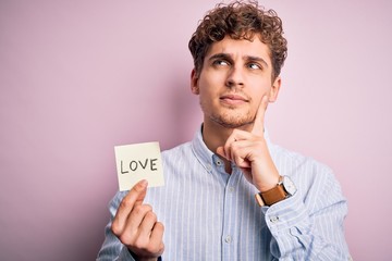 Young blond romantic man with curly hair holdiing paper with love message for valentines day...