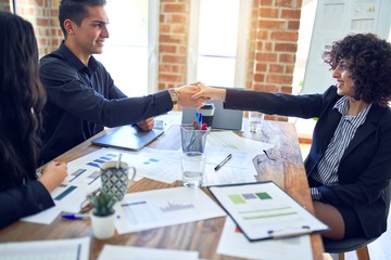 Group of business workers smiling happy and confident. Working together with smile on face shaking hands for agreement at the office