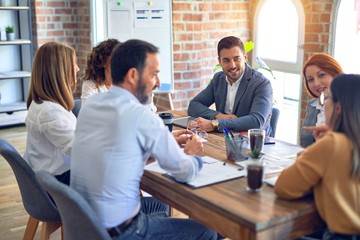 Group of business workers working together. Sitting on desk speaking at the office