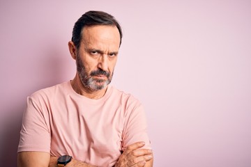Middle age hoary man wearing casual t-shirt standing over isolated pink background skeptic and...