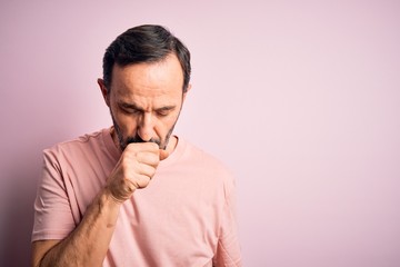 Middle age hoary man wearing casual t-shirt standing over isolated pink background feeling unwell and coughing as symptom for cold or bronchitis. Health care concept.