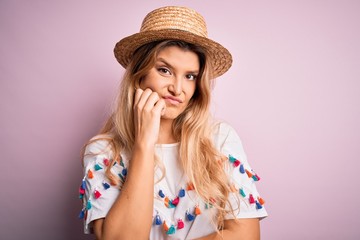 Young beautiful blonde woman wearing t-shirt and hat over isolated pink background thinking looking tired and bored with depression problems with crossed arms.