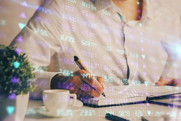 Double exposure of man's hands writing notes of stock market with forex chart.