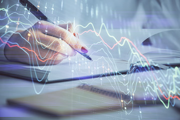 Multi exposure of woman's hands making notes with forex graph hologram. Concept stock market analysis.
