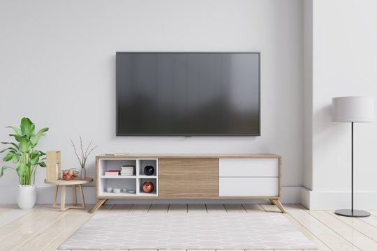 TV on the cabinet in modern living room with plant on white wall background.
