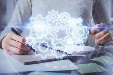 International business hologram over woman's hands taking notes background. Concept of success. Double exposure