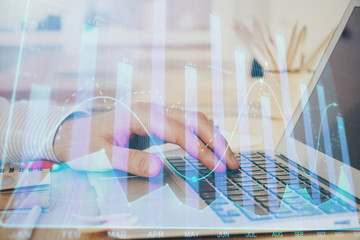 Obraz premium Double exposure of stock market graph with man working on laptop on background. Concept of financial analysis.