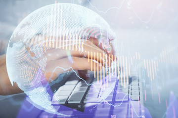 Multi exposure of graph with man typing on computer in office on background. Concept of hard work. Closeup.