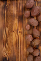 Fresh potatoes arranged on a wooden table top background to form a page border. Bio food