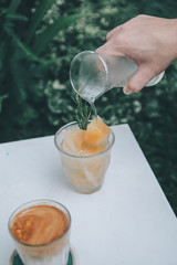 Pouring soda on plum juice ice cubes.A clear glass of iced Italian soda with Chinese plum syrup decorate with real Chinese plum. cocktail or mock tail concept. Selective focus.