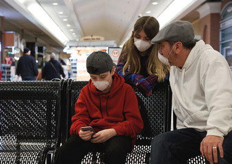 Family in Virus Masks Sitting in Public with Phone