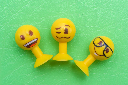 Smiley toy on a suction cup, three pieces on a green background