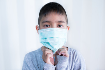 Portrait Asian kid wearing medical mask.A boy wearing mouth mask against air smog pollution....