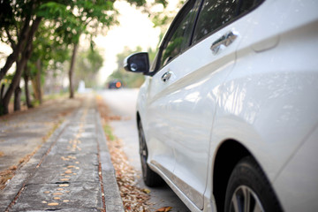 Fototapeta premium biały samochód na parkingu, Zamknij się po stronie białego samochodu na drodze