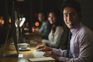 Portrait of Asian Male customer care service with businesswoman smiling and working hard late in...