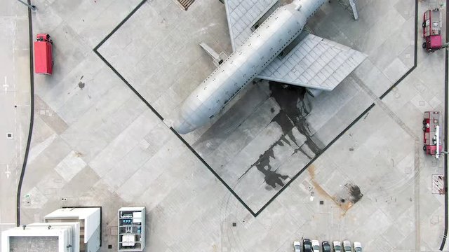 Top down aerial view of a simulation training facility for Aircraft emergency scenario , with a Large airplane and Fire trucks.