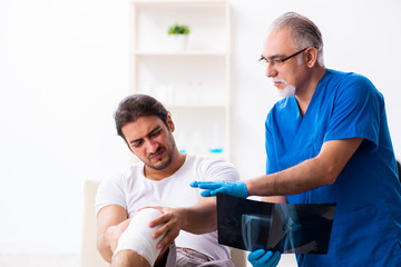 Fototapeta premium Leg injured man visiting old doctor in first aid concept