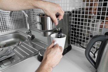 Guy prepare delicious aromatic coffee in a coffee machine. A simple way to make coffee