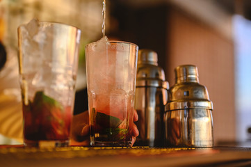The bartender opens a bottle of red wine using a wine opener. To pour a lot of empty glasses at the bar counter. Blurred background. wine, tasting, open, beverage, bartender, dinner concept.