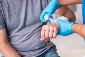 Young male doctor and old patient in first aid concept