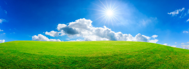Green grass field and blue sky with white clouds,panoramic view.