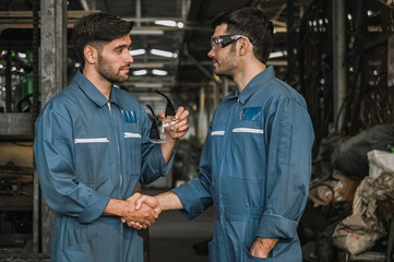 happy engineer men wearing uniform safety in factory shaking hand talking relax time working.
