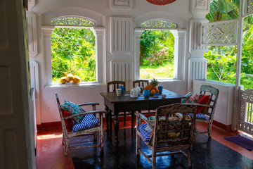 Breakfast a healthy diet of fruits and vegetables on a table of antique furniture, shabby chairs on the terrace of an authentic European colonial-style Villa with tropical garden. Sri Lanka Asia