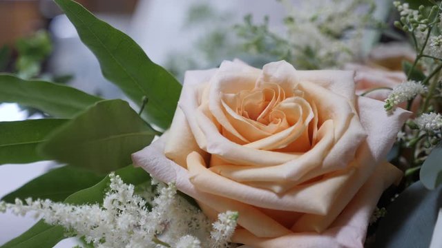 Wedding bouquet details. Close up shot of the light pink rose with green leaves and white floral arrangement