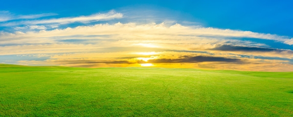 Obraz na płótnie Canvas Green grass field and colorful sky clouds at sunset,panoramic view.