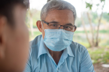 Asian Doctor face mask checking heart rate by hand