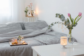 interior of bedroom with flowers, candles and cup of tea