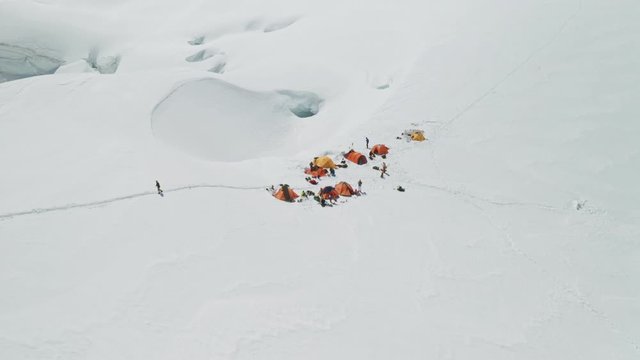 Alpinists camp on white wide snow mountain slope, highland mountaineers base