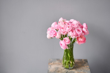 Spring background, flower Wallpaper. Persian buttercup. Bunch pink ranunculus flowers on light gray background. Vase on vintage wooden table. Wallpaper