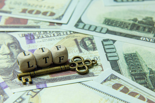 ltf  wooden cube and gold key on banknotes for business content.
