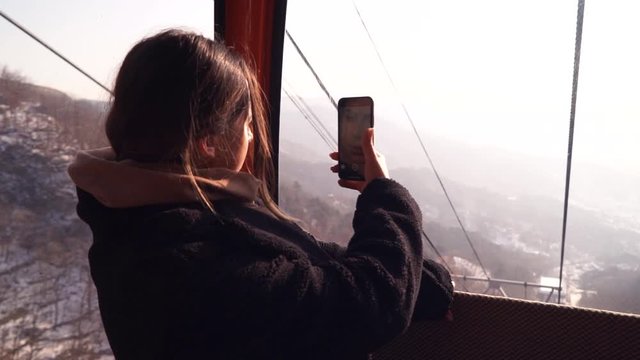 Tourist girl taking pictures from a cableway of Great wall panoramic view.