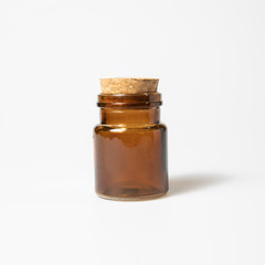 front view of transparent empty brown glass jar bottle with closed cork cap lids on white background